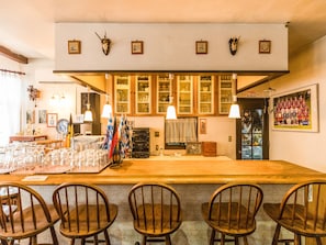 A bar area with wooden chairs, a counter with glasses, and cabinets above.