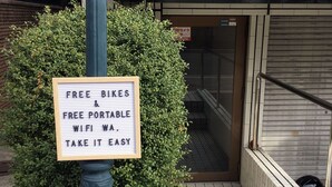 A sign offering free bikes and portable WiFi, placed on a pole beside a building entrance. - Free bike and free WIFI 204 Take it easy (Kyoto)