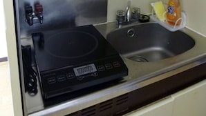 A kitchen with a built-in induction cooktop, a stainless steel sink, and a small shelf above the sink. - Free bike and free WIFI 204 Take it easy (Kyoto)