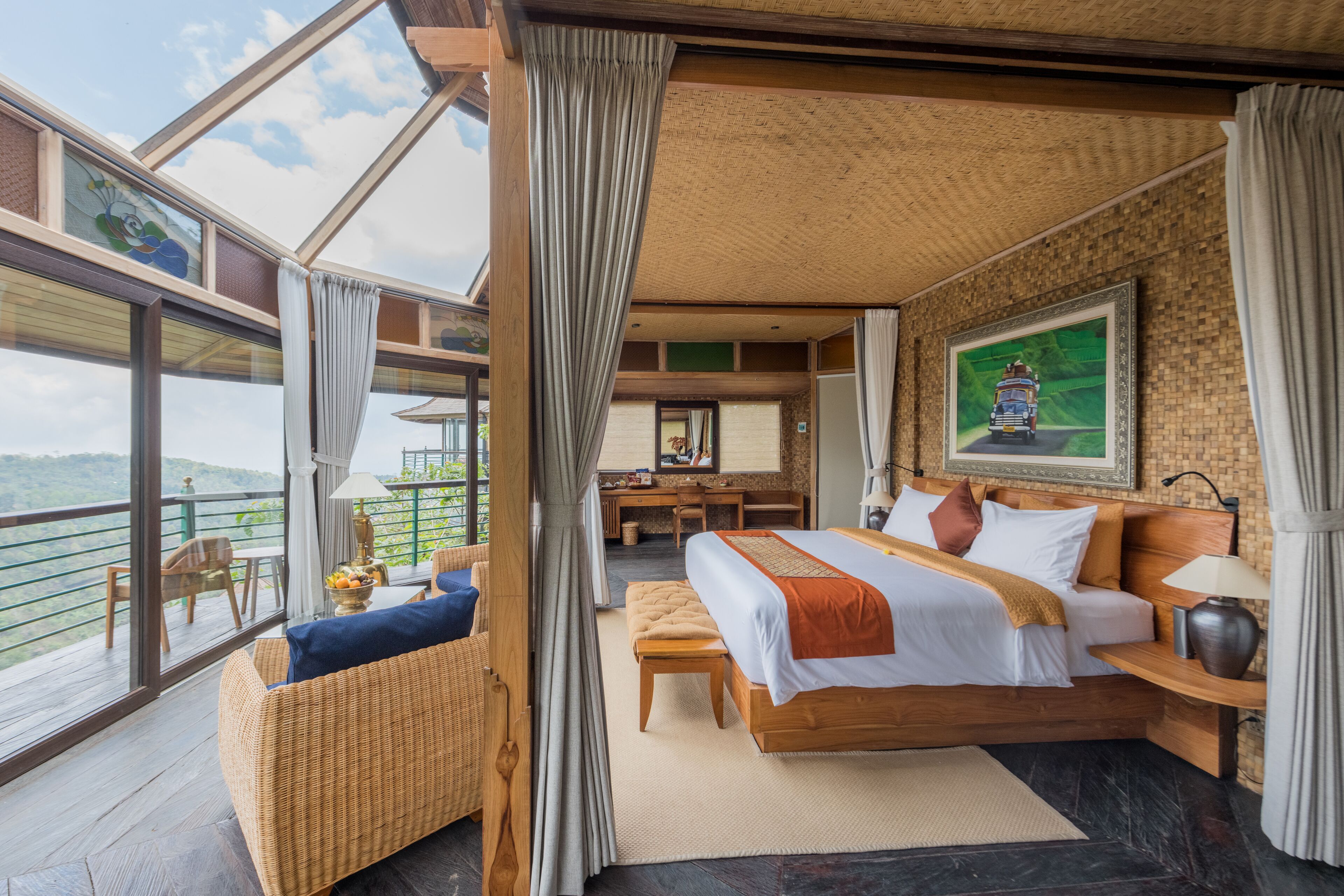 A spacious bedroom with a large bed, a desk, and a balcony with a view.