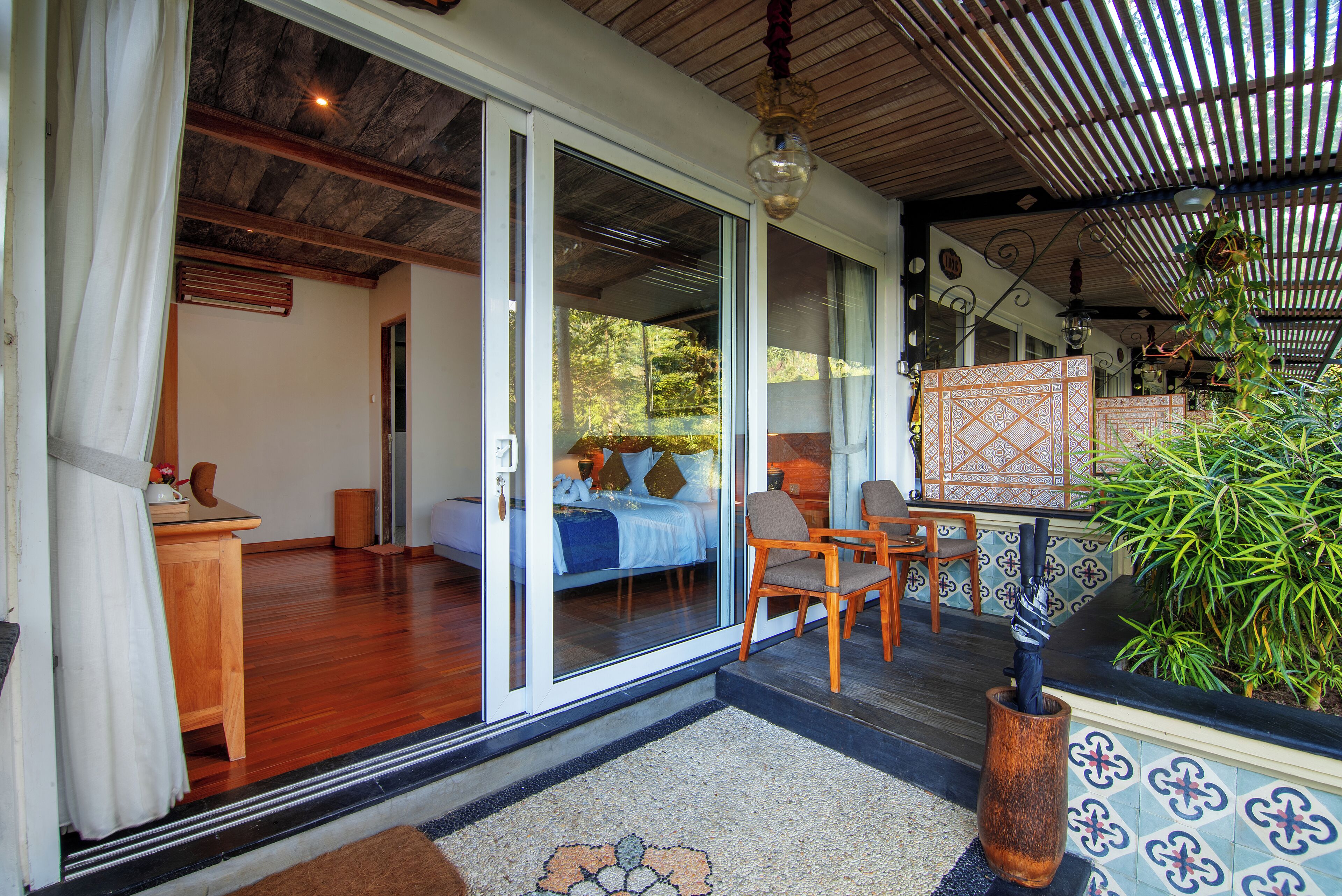 A room with a bed, a chair, a small table, and a large window.