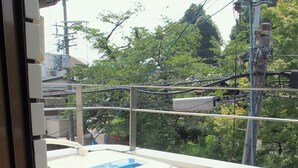 Máquina de lavar roupa branca numa varanda, com vista para árvores e linhas de eletricidade.