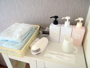 A bathroom vanity with a towel rack holding folded towels, a hairdryer, two bottles of shampoo and conditioner, a body wash bottle, and two toothbrushes. - Free bike & free WIFI 301 Take it easy (Kyoto)