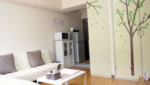 Uma sala de estar moderna com um sofá branco, uma mesa de centro e uma geladeira.