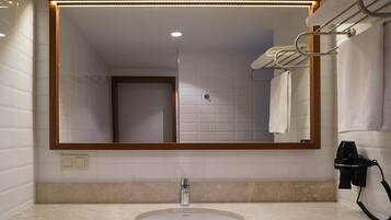 A bathroom with a large mirror, a sink, and a towel rack.