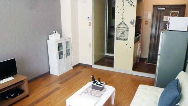 Una sala de estar con televisor, un mueble blanco, una mesa de centro y un sofá con cojines a rayas.