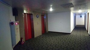 A hallway with two elevators, carpeted floors, and a fire extinguisher. - Dreamer Hotel (Budai)