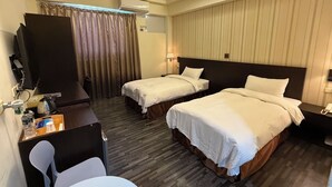 A hotel room with two beds, a desk, a chair, a TV, and an air conditioning unit. - Dreamer Hotel (Budai)
