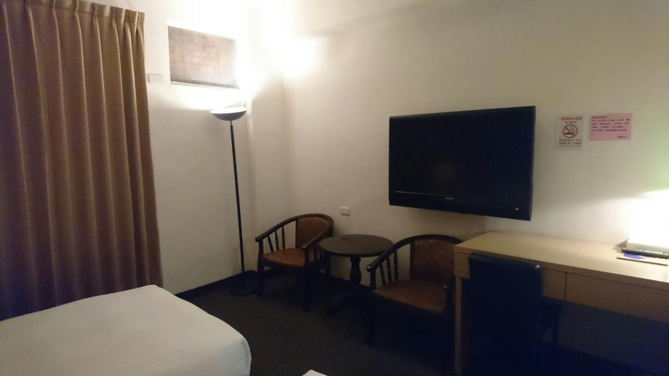 Ein Hotelzimmer mit Bett, Schreibtisch, Fernseher und zwei Sesseln.
