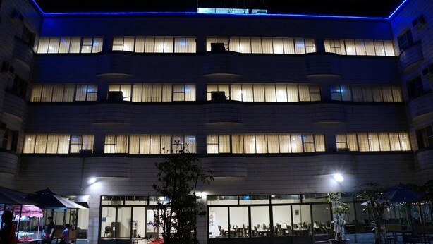 A multi-story hotel with illuminated windows and a blue neon outline. - Dreamer Hotel (Budai)