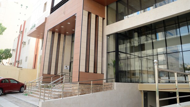 A modern building with large windows, a staircase, and a red car parked nearby. - Beyab Al Azizeyyah Hotel (Makkah)