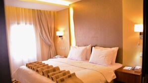 A hotel room with a large bed, two bedside lamps, a nightstand, and a window with curtains. - Beyab Al Azizeyyah Hotel (Makkah)