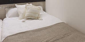 Una cama bien hecha con ropa de cama blanca y un edredón estampado.