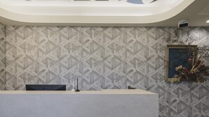 Un mostrador de recepción con un papel tapiz estampado y un cuadro enmarcado.
