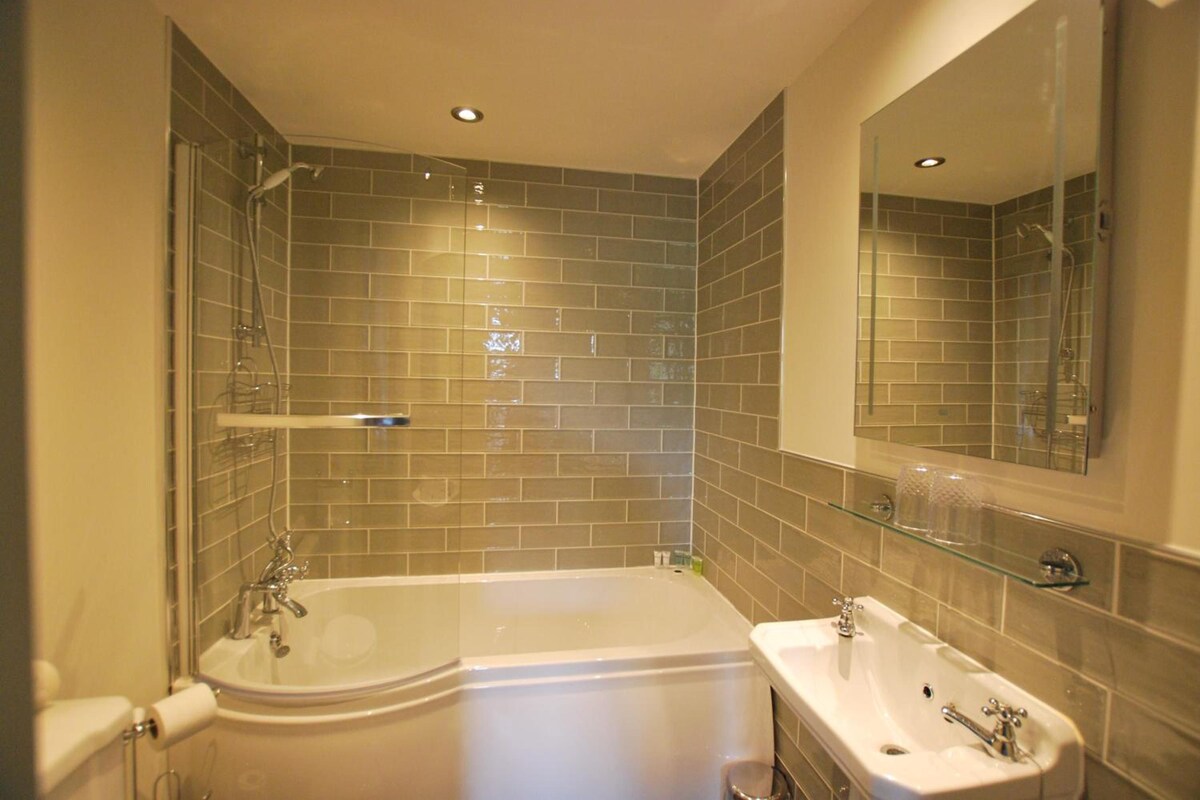 A modern bathroom with a freestanding bathtub, a vanity with a sink, and a large mirror.