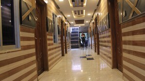 Um corredor com paredes listradas, piso lustroso e escada que leva a um andar superior.