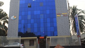 Um hotel com fachada de vidro moderna e uma placa indicando ser o Rose Valley Hotel & Resort.