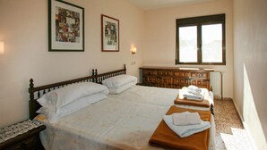 A bedroom with a large bed, a dresser, and two framed pictures on the wall.