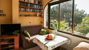 A cozy living room with a sofa, a television, a bookshelf, and a table with a fruit bowl.