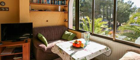 A cozy living room with a sofa, a television, a bookshelf, and a table with a fruit bowl.