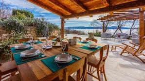 A wooden dining table set for a meal with a view of mountains and a lake. - Villa Jelena (Novi Vinodolski)