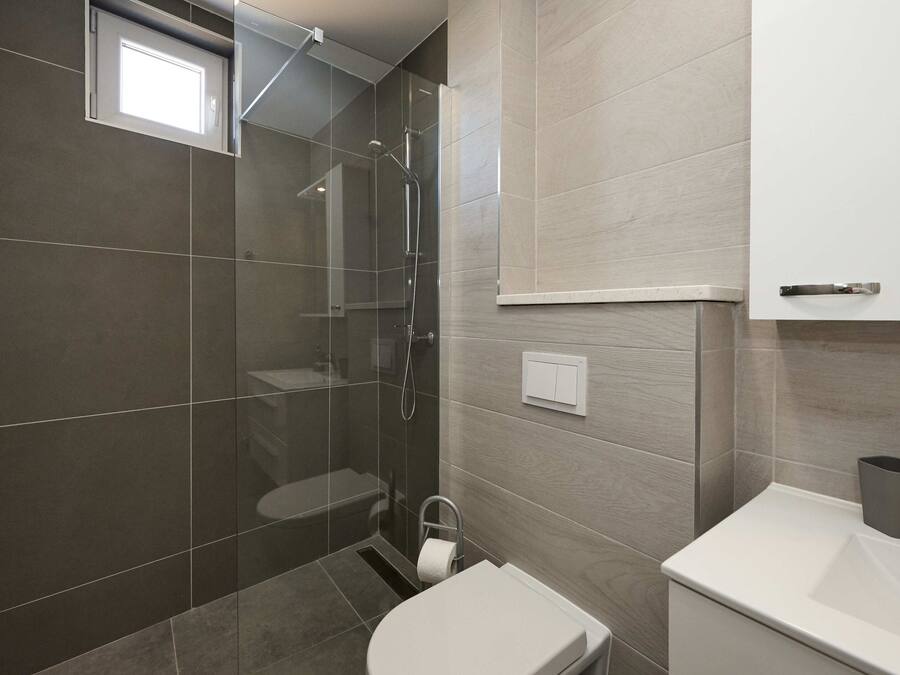 A modern bathroom with a glass-enclosed shower, a toilet, and a sink.