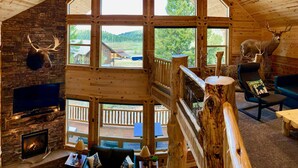Ein Holzblockhaus-Interieur mit einem Steinkamin, einem aufgehängten Elchgehörn und einem Reh-Kopf an der Wand.