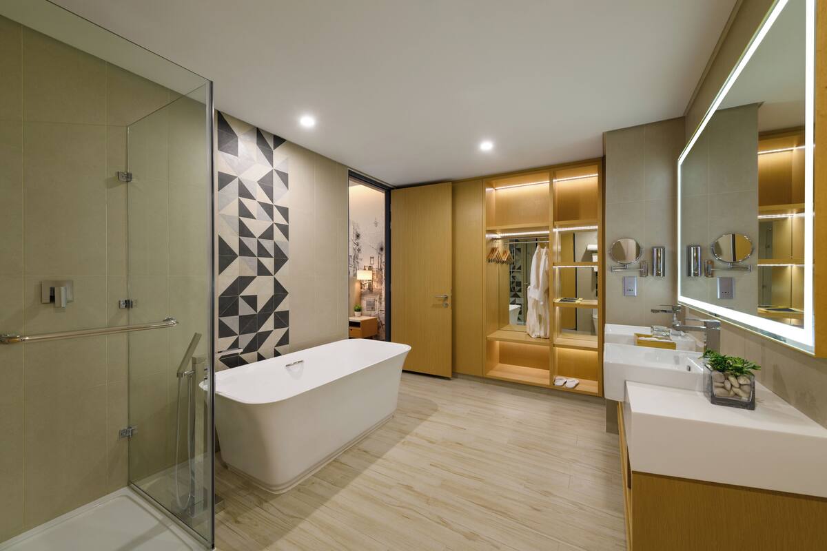 A modern bathroom with a glass shower enclosure, a freestanding bathtub, and a vanity with a large mirror.