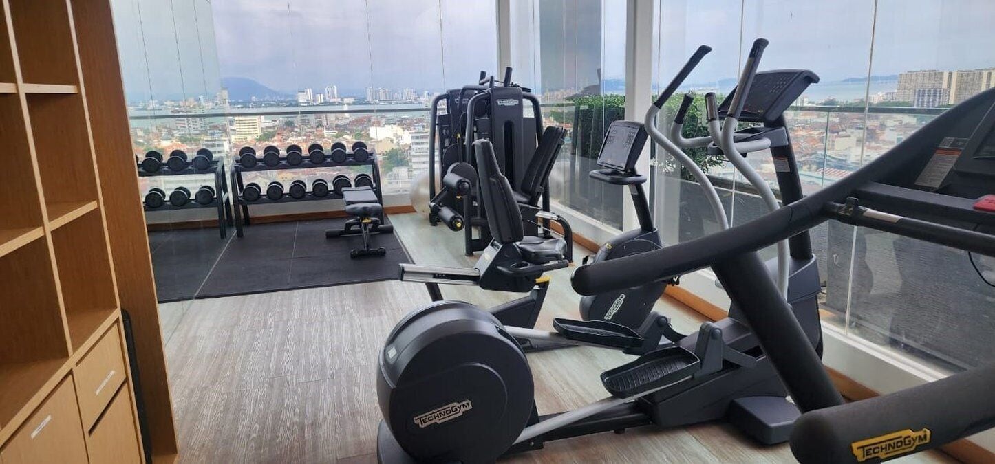 Un gimnasio con máquinas de cardio, equipo de levantamiento de pesas y mancuernas.
