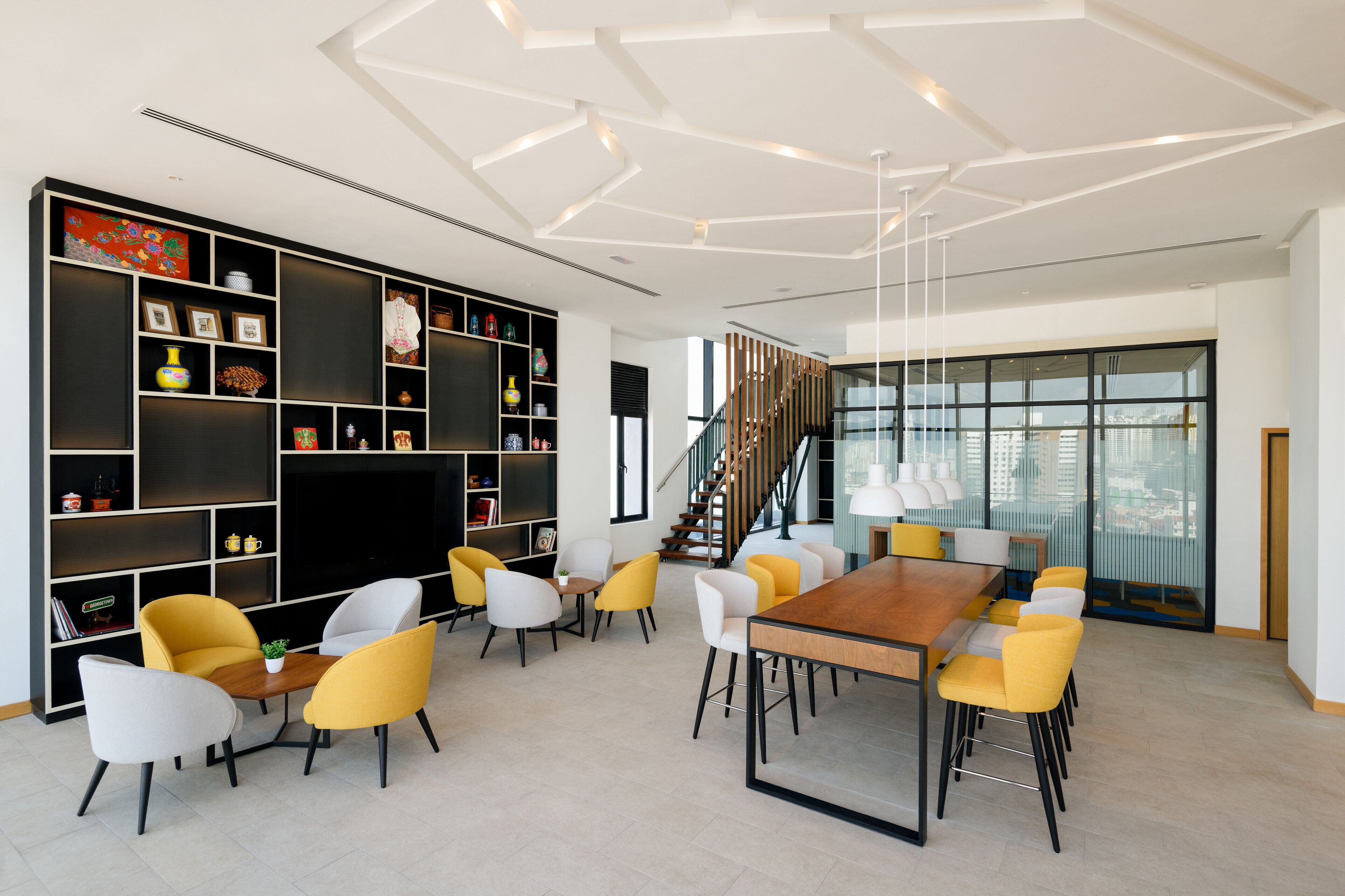 A modern interior with a dining area, bookshelves, and a staircase.