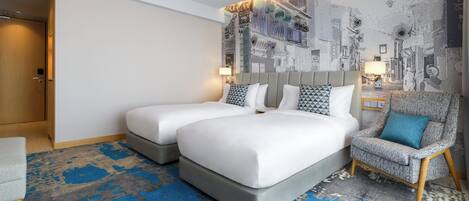 A hotel room with a large bed, two bedside tables, a chair, and a patterned carpet.