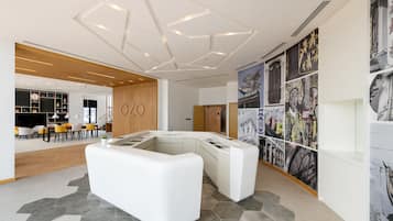 Un vestíbulo moderno con un mostrador de recepción blanco, suelo de patrón hexagonal y una pared de listones de madera.