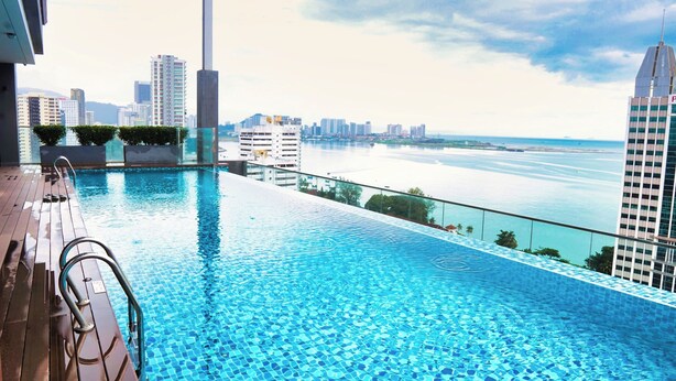A rooftop infinity pool with a city view, surrounded by modern buildings and a body of water. - OZO George Town Penang (George Town)
