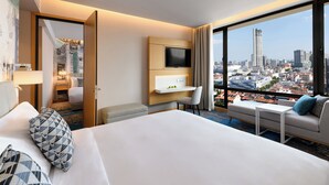 A hotel room with a large bed, a TV, a desk, and a sofa. The room has a city view. - OZO George Town Penang (George Town)