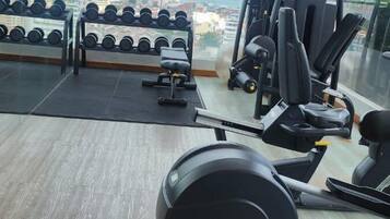Un gimnasio con una máquina de remo, mancuernas y bancos de pesas.