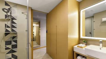 A modern bathroom with a shower, a large mirror, and a wooden vanity.