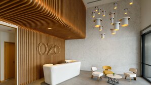 A modern reception area with a white reception desk, wooden slatted wall, and multiple seating options including a round table and chairs. - OZO George Town Penang (George Town)