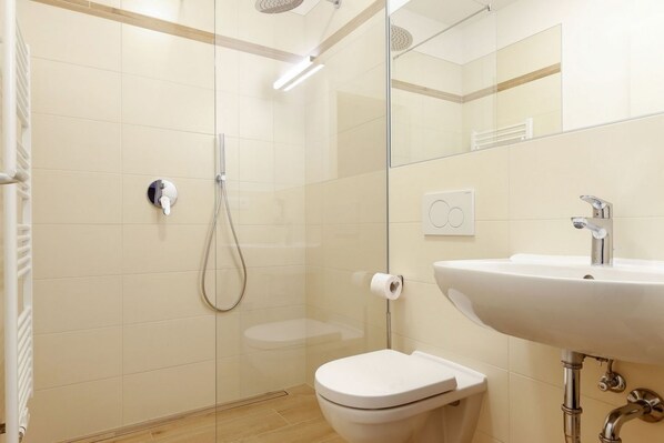 Un baño moderno con cabina de ducha de vidrio, inodoro blanco y lavabo con espejo.