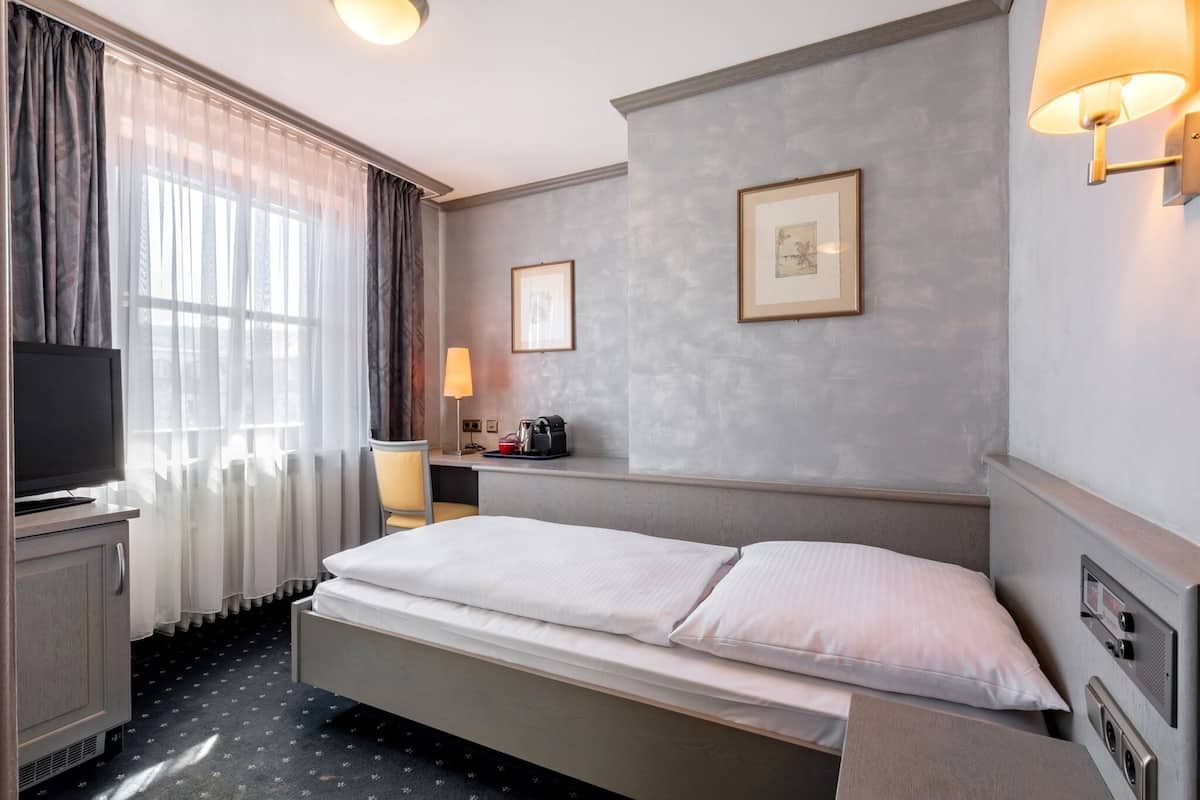 Une chambre d’hôtel avec un lit, une télévision, un bureau avec une lampe et des tableaux encadrés au mur.
