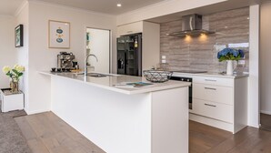 A modern kitchen with a central island, stainless steel appliances, and a marble backsplash.
