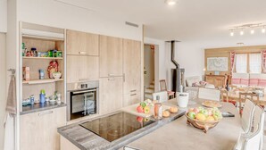 Una cocina moderna con electrodomésticos integrados, una isla central con fruta y una zona de comedor con mesa y sillas.