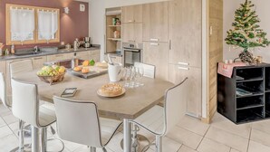 Una cocina moderna con una isla central, sillas blancas y un árbol de Navidad.