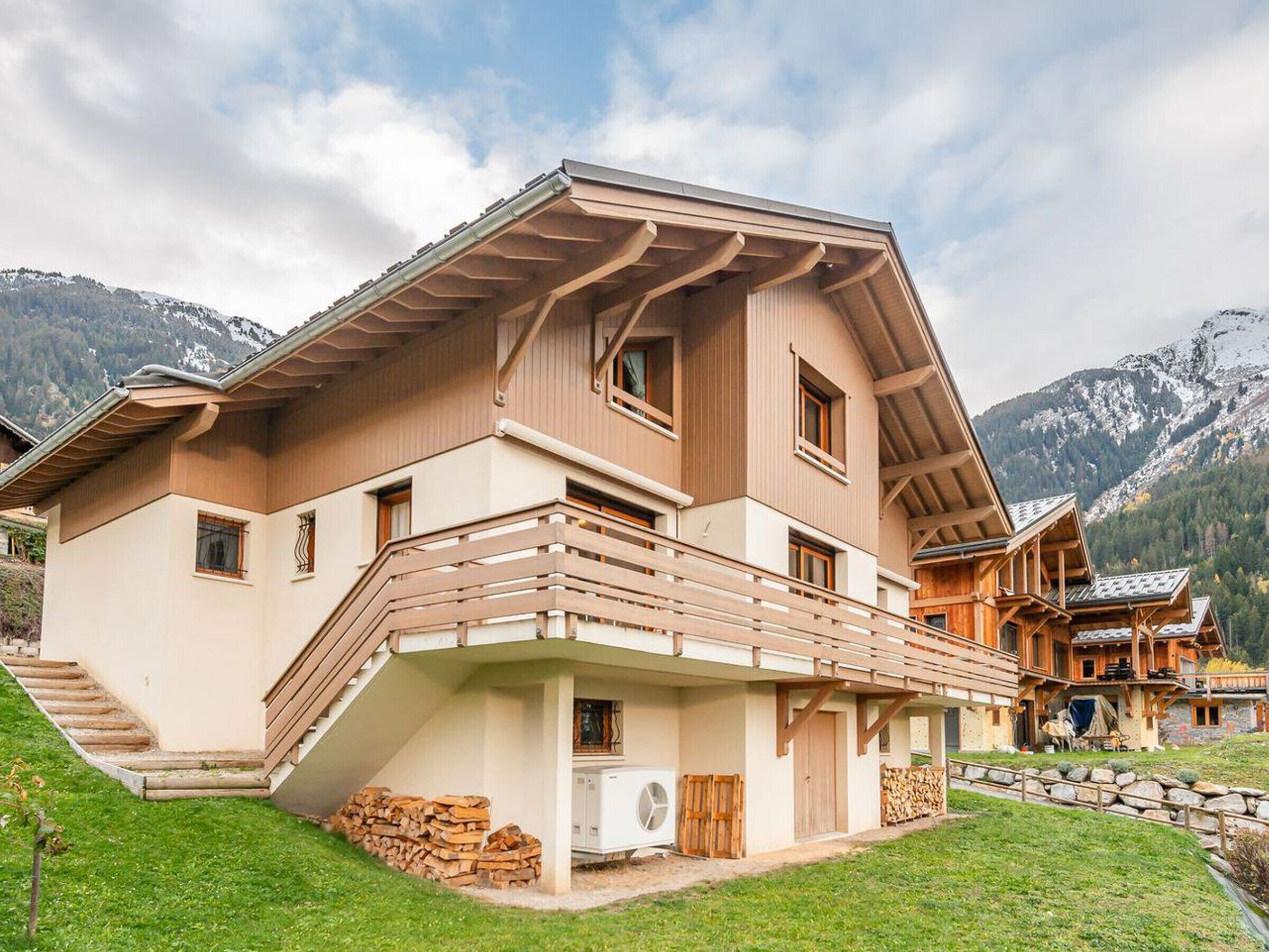 Een modern chalet met een schuin dak, houten balkons en een stenen fundering.