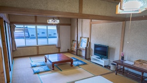 A traditional Japanese room with tatami flooring, a television, and a small table. - Ryokan Fuji Heights (Fujikawaguchiko)