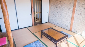 A tatami mat room with a low wooden table, sliding doors, and a view of a traditional Japanese room. - Ryokan Fuji Heights (Fujikawaguchiko)
