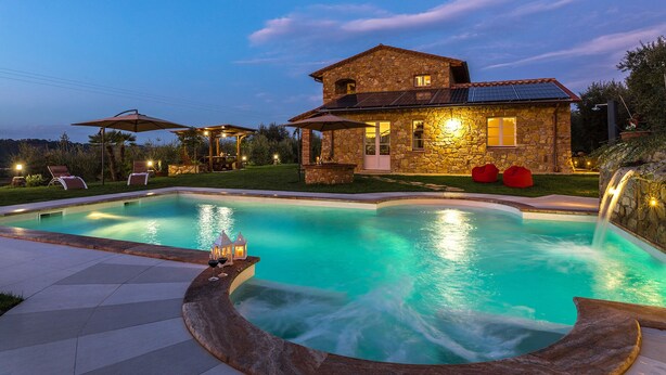 Une maison en pierre dotée d’une piscine, d’un espace extérieur aménagé et d’une cascade.