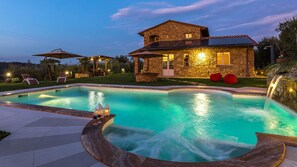 Une maison en pierre dotée d’une piscine, d’un espace extérieur aménagé et d’une cascade.