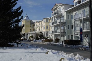 Un hotel con varios pisos, balcones y una calle cubierta de nieve.