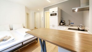 Een compacte hotelkamer met een bed, een klein kitchenette en een houten tafeltje.