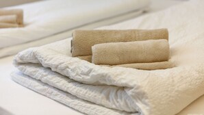 Een net opgemaakt bed met witte en beige lakens.